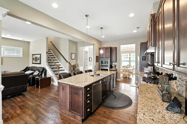 a large kitchen with kitchen island a stove a refrigerator a dining table and chairs with wooden floor