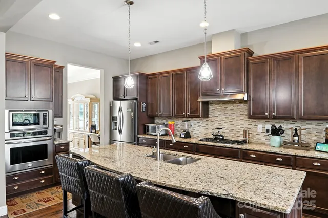 a kitchen with granite countertop a sink stove and refrigerator