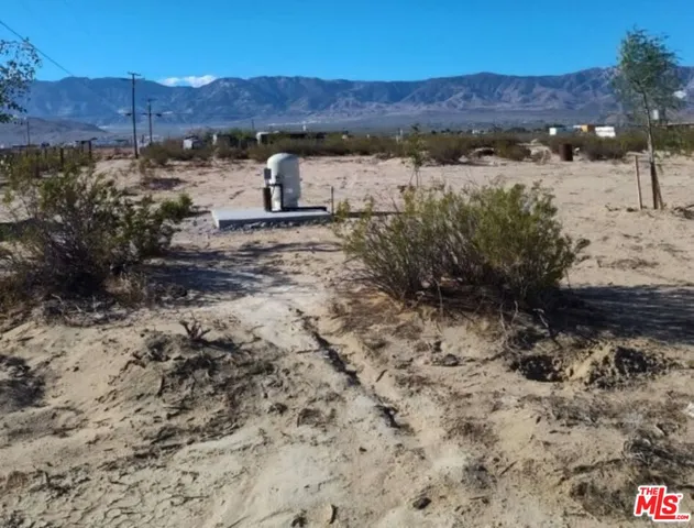 a view of a dry field with mountains in the background