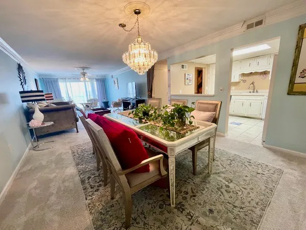 a view of a dining room and livingroom with furniture wooden floor and a chandelier