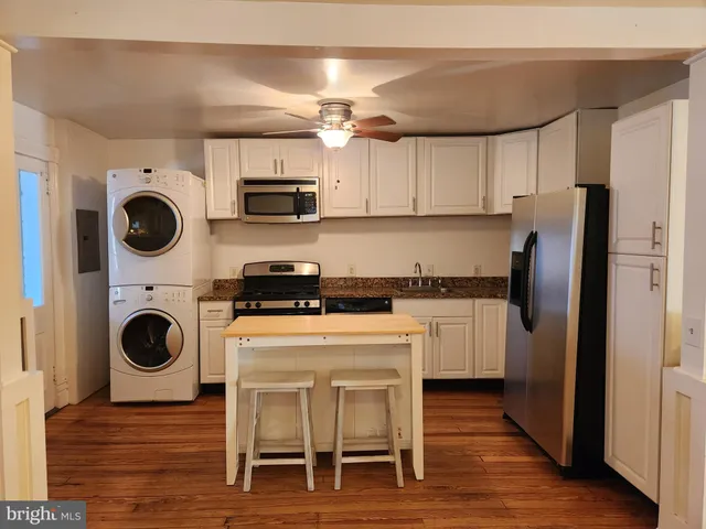 a kitchen with a refrigerator a microwave oven cabinets and wooden floor