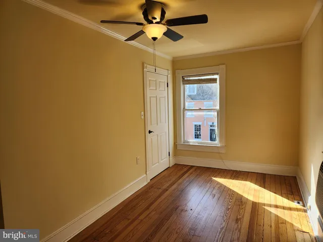 a view of empty room with wooden floor and fan