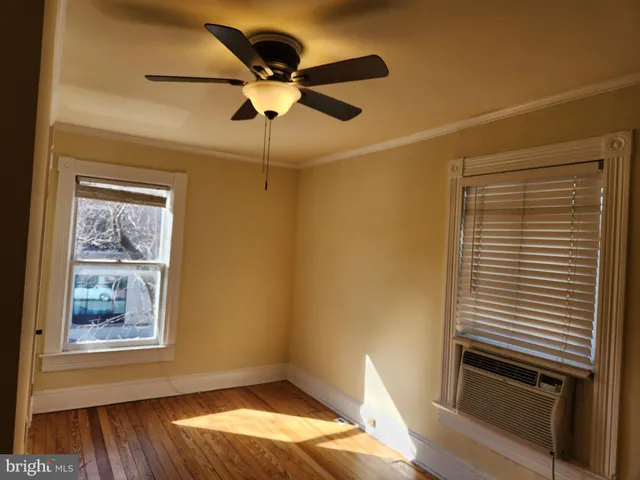 a view of empty room with wooden floor and fan