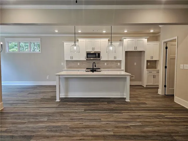 a kitchen with kitchen island a stove a sink a window and wooden floor