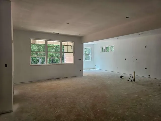 a view of an empty room with wooden floor fireplace and a window