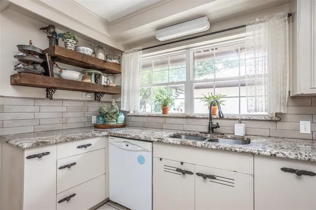 a kitchen with stainless steel appliances granite countertop white cabinets and a window