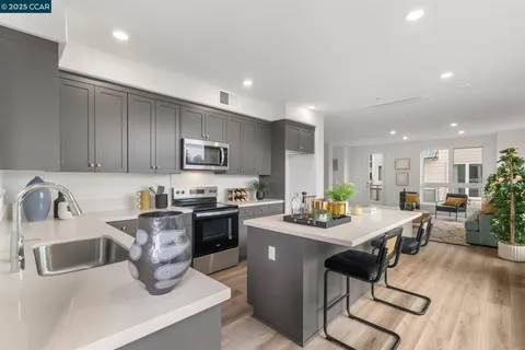 a kitchen with a sink dishwasher a stove a kitchen island with chairs and wooden floor