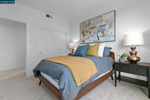 a bedroom with a bed and a lamp on dresser