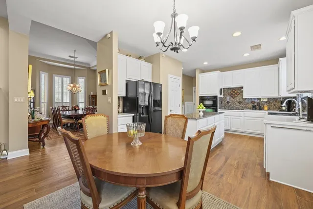 a kitchen with sink stove and white cabinets with wooden floor