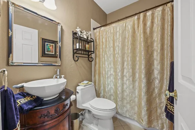a bathroom with a sink a toilet a mirror and shower curtain