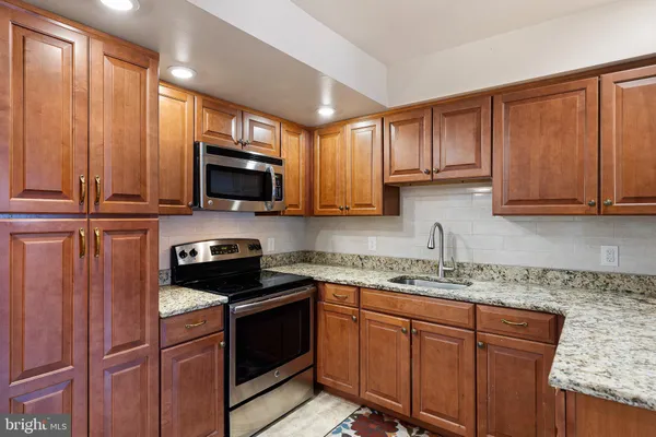a kitchen with stainless steel appliances granite countertop wooden cabinets a stove a sink and a microwave