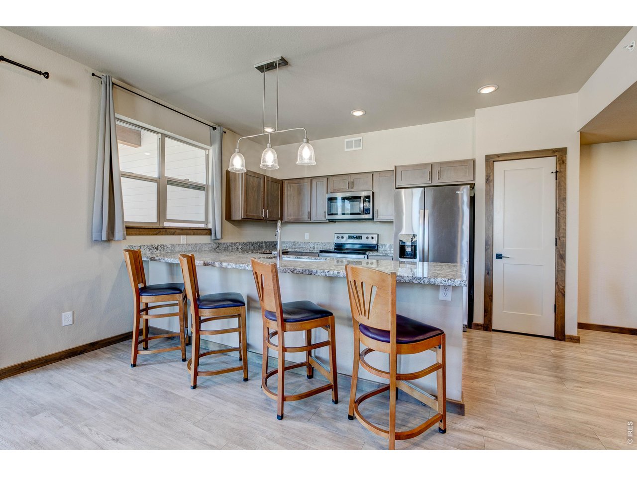1802 Wildfire Road, Unit 204 Estes Park, CO 80517 - Photo 10 of 35 a kitchen with stainless steel appliances kitchen island granite countertop a dining table chairs refrigerator and sink