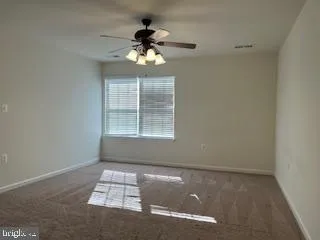 an empty room with wooden floor chandelier fan and windows