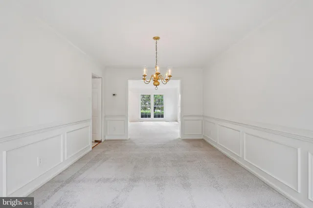 a view of an empty room with chandelier fan and windows