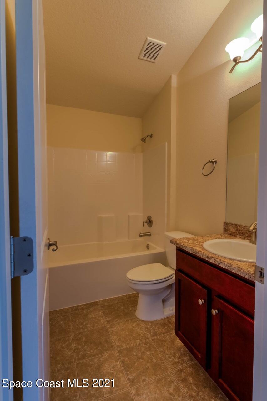 784 Moment Circle Cocoa, FL 32926 - Photo 11 of 14 a bathroom with a granite countertop sink a toilet a mirror and bathtub