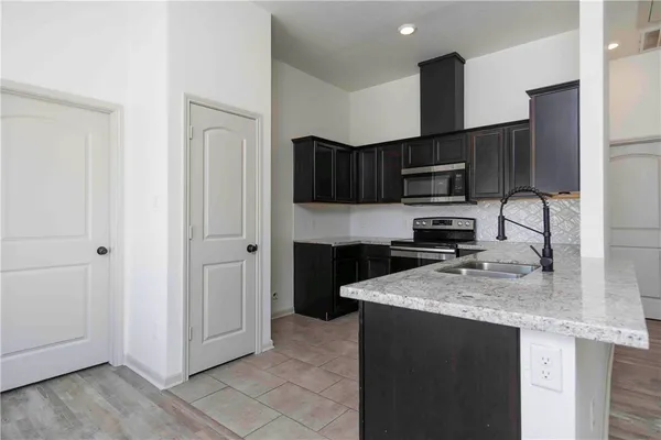 a kitchen with stainless steel appliances granite countertop a refrigerator a sink a stove a microwave and wooden cabinets