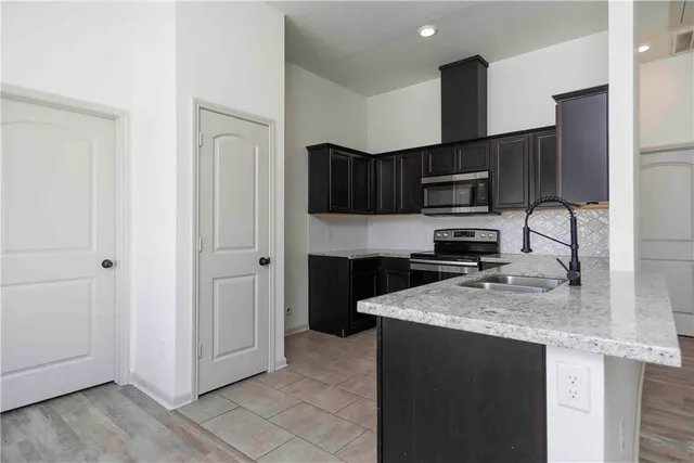 a kitchen with stainless steel appliances granite countertop a refrigerator a sink a stove a microwave and wooden cabinets