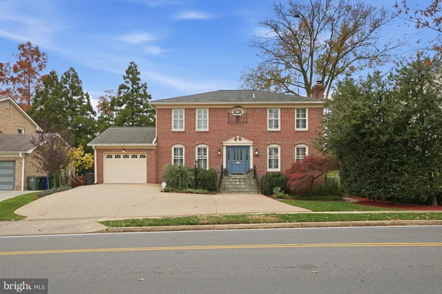 a view of a brick house with a big yard and large trees