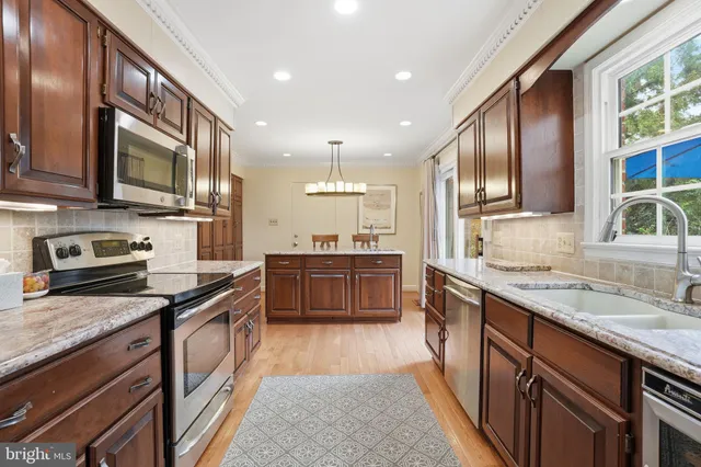 a kitchen with stainless steel appliances granite countertop a stove top oven a sink dishwasher a refrigerator and cabinets with wooden floor