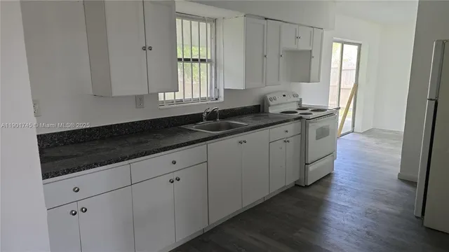 a kitchen with granite countertop white cabinets and a sink