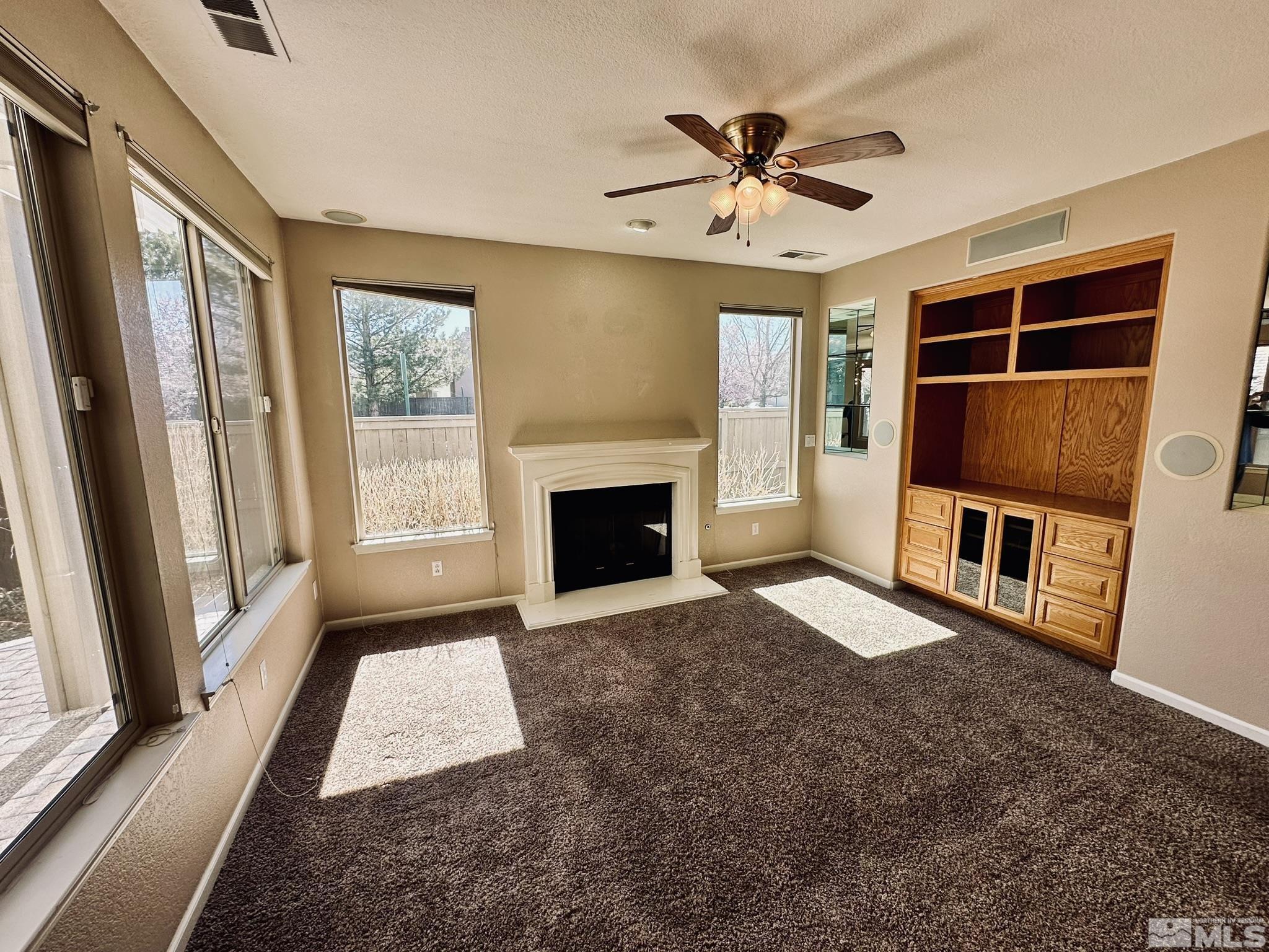 491 Oldenburg Drive Reno, NV 89521 - Photo 7 of 36 a living room with a fireplace furniture a ceiling fan and a window