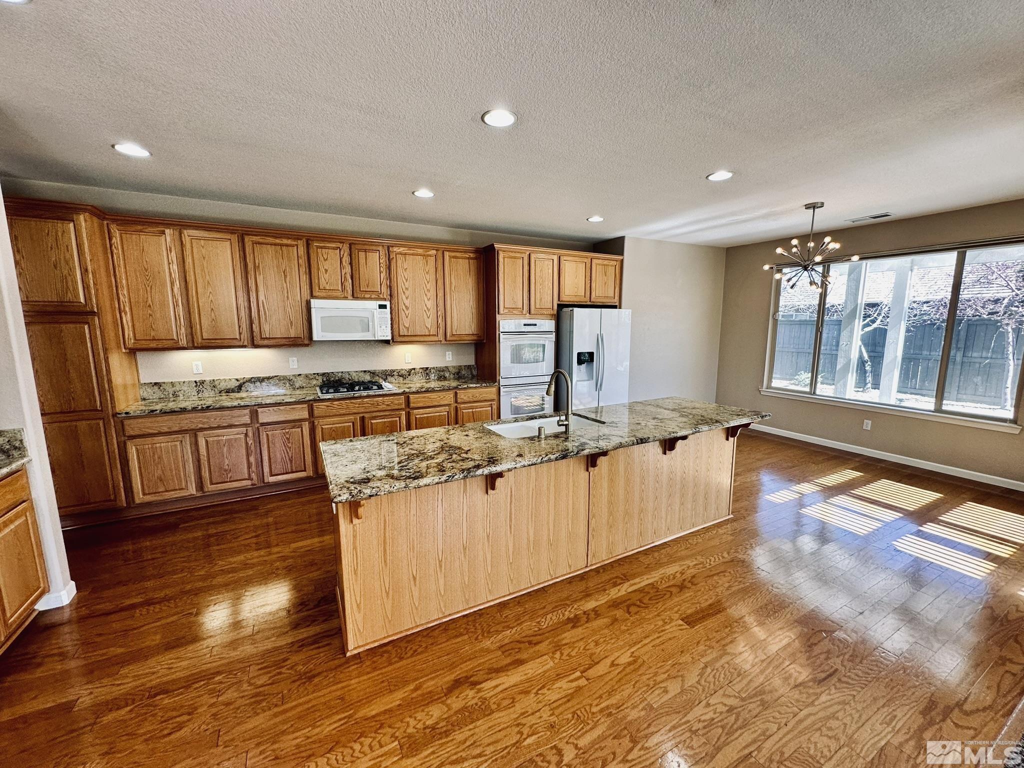 491 Oldenburg Drive Reno, NV 89521 - Photo 9 of 36 a large kitchen with stainless steel appliances granite countertop a lot of counter space and wooden floors