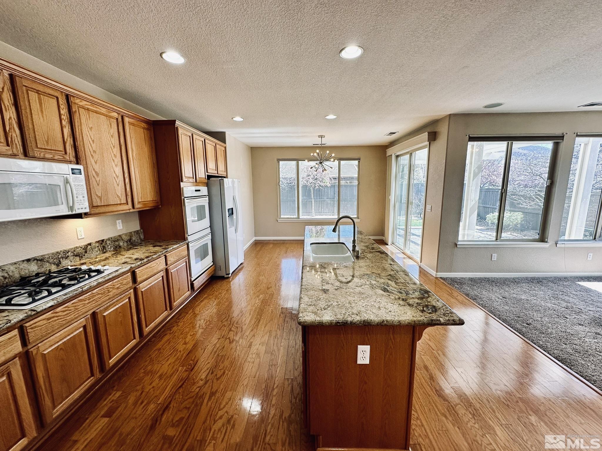 491 Oldenburg Drive Reno, NV 89521 - Photo 10 of 36 a kitchen with stainless steel appliances granite countertop wooden cabinets a stove top oven a sink and dishwasher with wooden floor