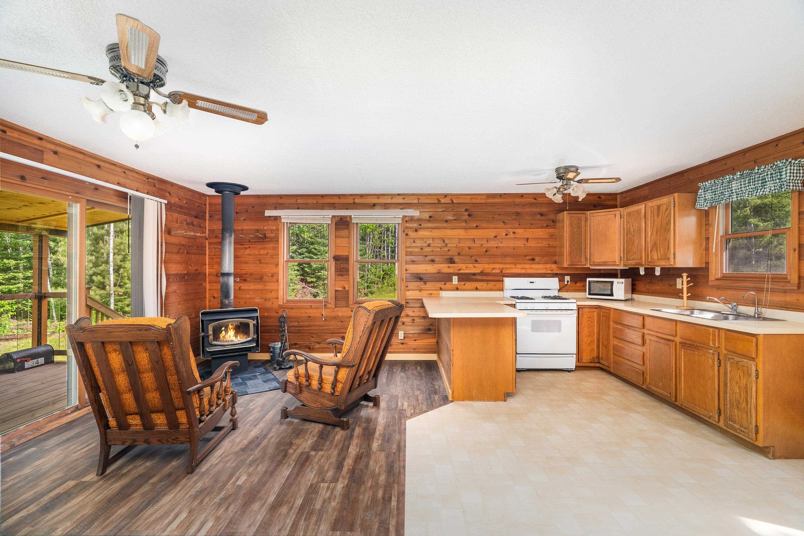 1612 Pequaywan Lake Road Brimson, MN 55602 - Photo 13 of 45 Kitchen featuring white appliances, a ceiling fan, light countertops, a wood stove, and wood walls