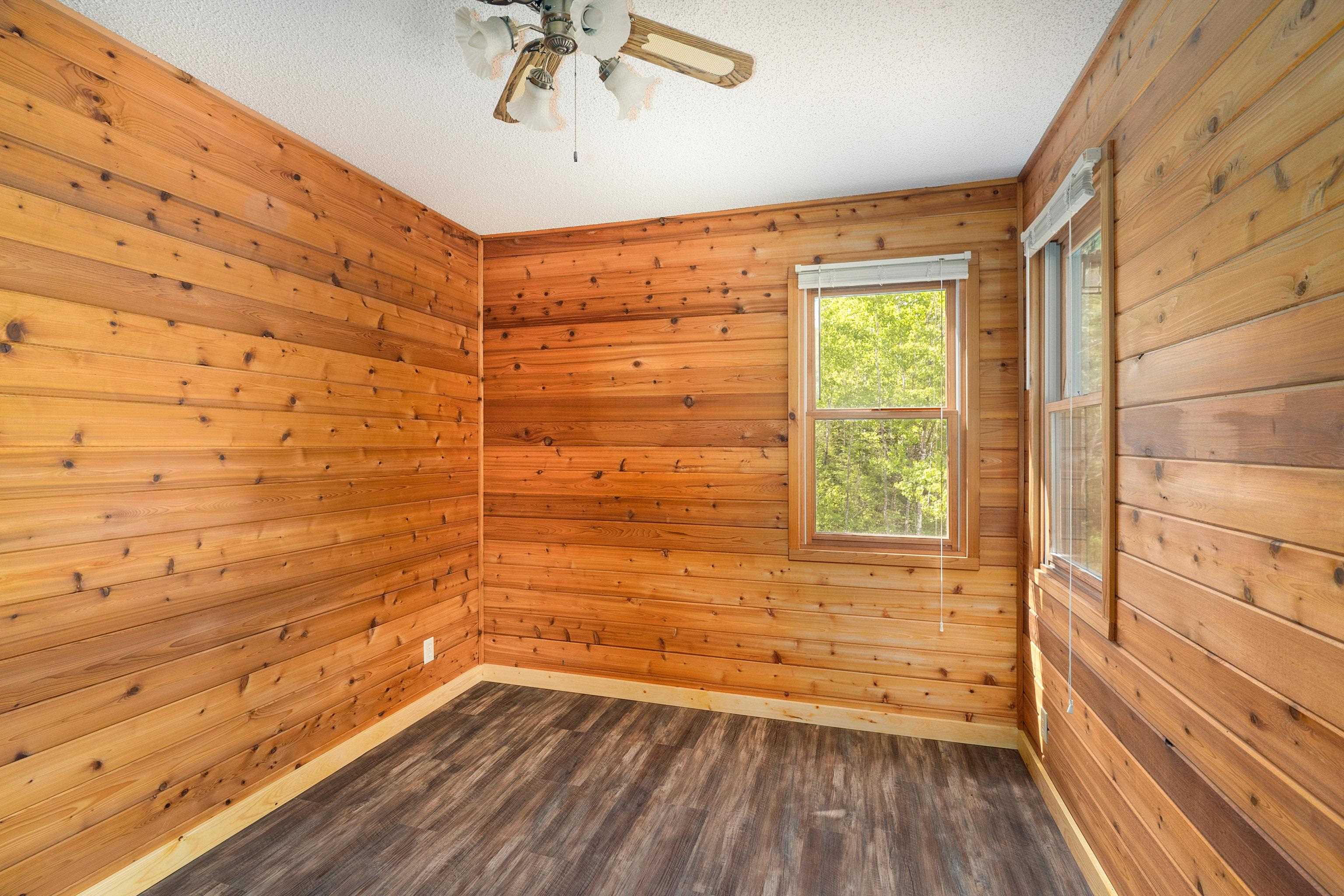 1612 Pequaywan Lake Road Brimson, MN 55602 - Photo 23 of 45 Spare room with dark wood-type flooring, wood walls, a ceiling fan, and a textured ceiling
