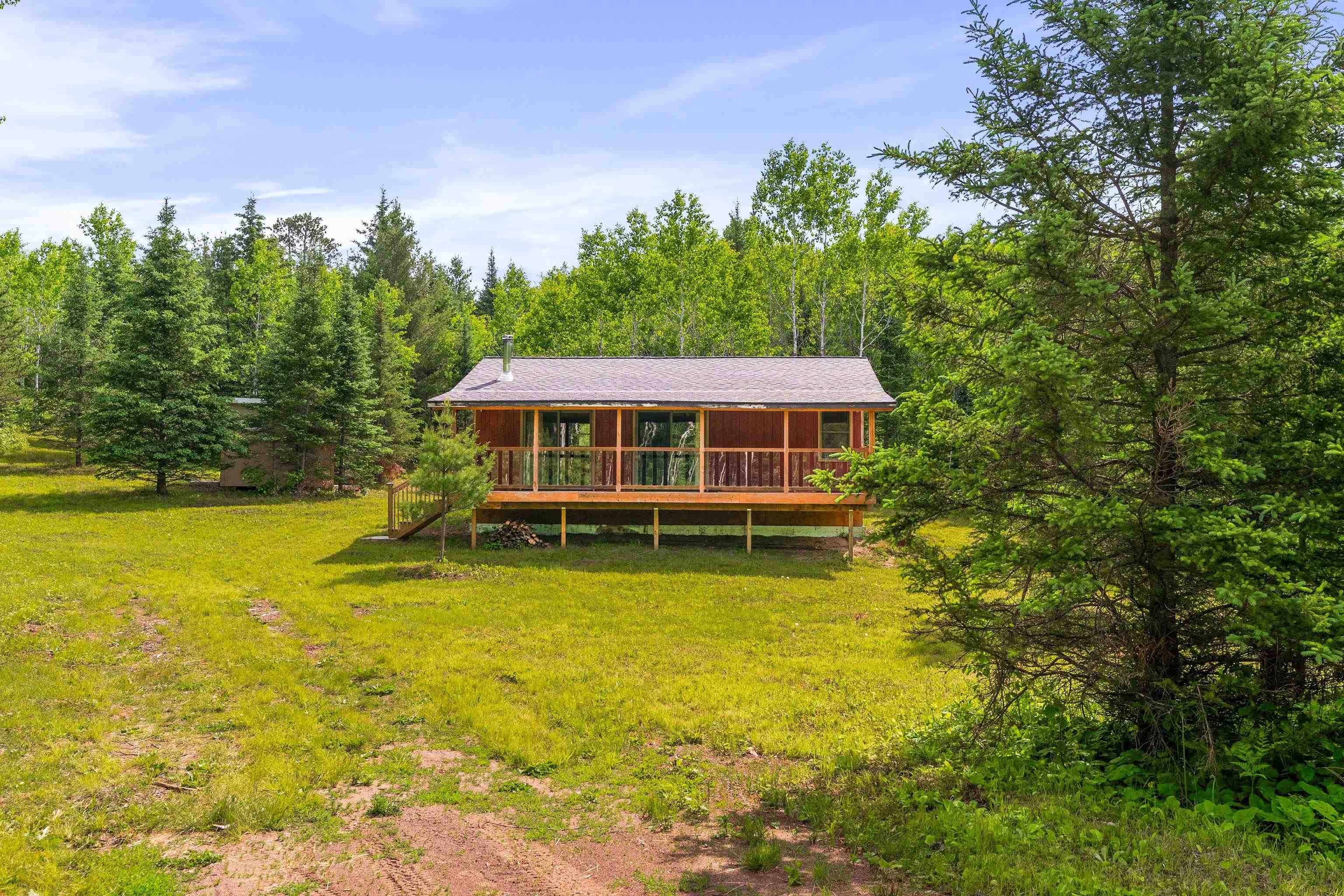 1612 Pequaywan Lake Road Brimson, MN 55602 - Photo 7 of 45 Back of property featuring a lawn, a deck, a wooded view, and a sunroom
