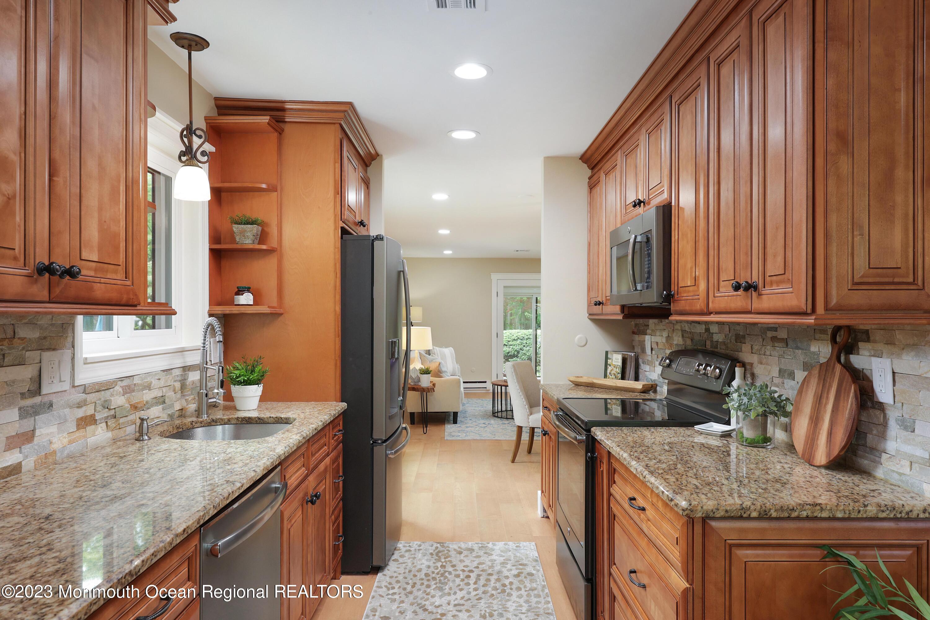 29 Manchester Court Red Bank, NJ 07701 - Photo 11 of 49 a kitchen with stainless steel appliances granite countertop a sink a stove and a wooden cabinets