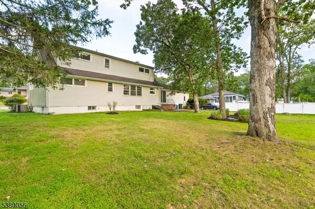 a view of a house with a big yard and large trees