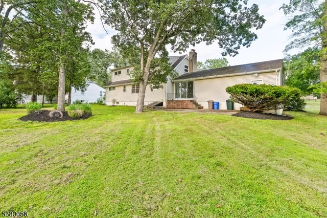 a view of a house with a yard and large trees