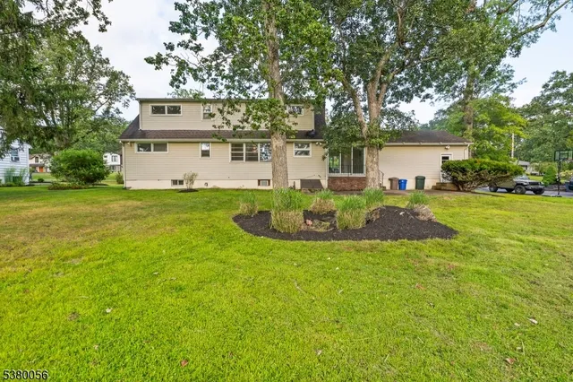 a view of a house with a big yard and large trees