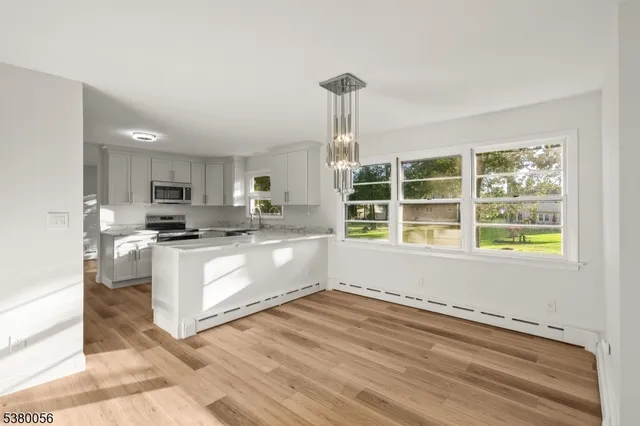 a kitchen with stainless steel appliances granite countertop a sink a stove a refrigerator and white cabinets with wooden floor