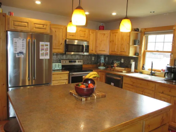 a kitchen with a refrigerator a stove a sink and a dining table with wooden floor