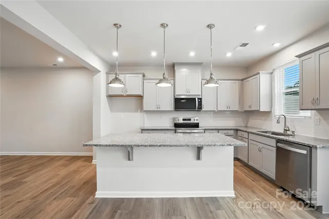 a large kitchen with stainless steel appliances granite countertop a stove a sink and a refrigerator