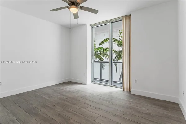 an empty room with wooden floor fan and windows