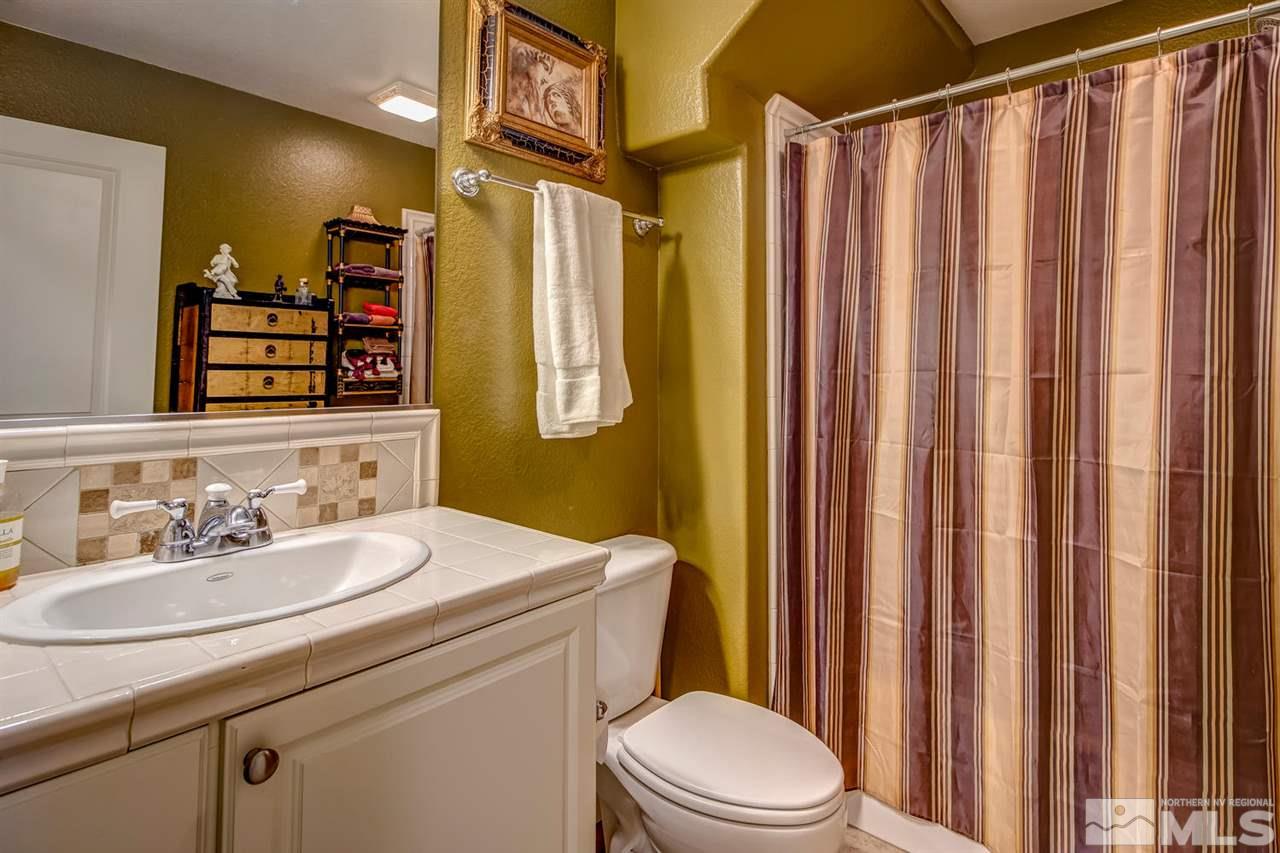 7675 Pebblestone Way Reno, NV 89523 - Photo 11 of 25 a bathroom with a sink a toilet a mirror and shower curtain