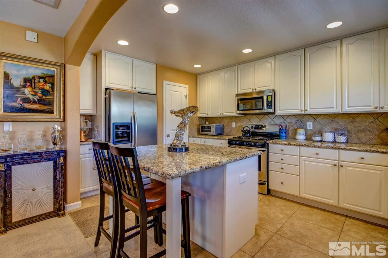 7675 Pebblestone Way Reno, NV 89523 - Photo 8 of 25 a kitchen with stainless steel appliances granite countertop a stove a sink a refrigerator a microwave oven with a dining table and chairs