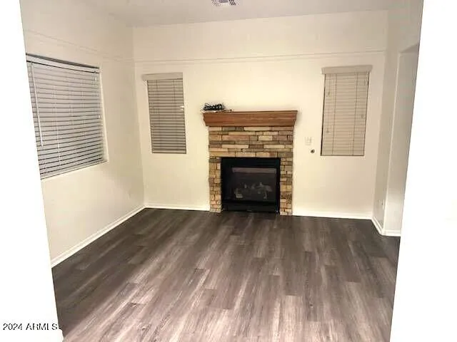 a view of an empty room with wooden floor fireplace and a window