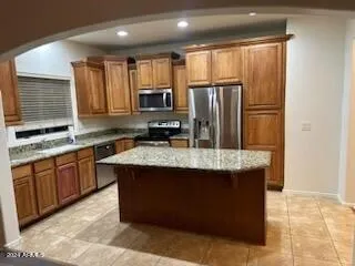 a kitchen with kitchen island granite countertop stainless steel appliances a sink stove refrigerator and cabinets