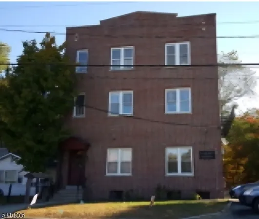 a red brick house that has window in it and trees in the background