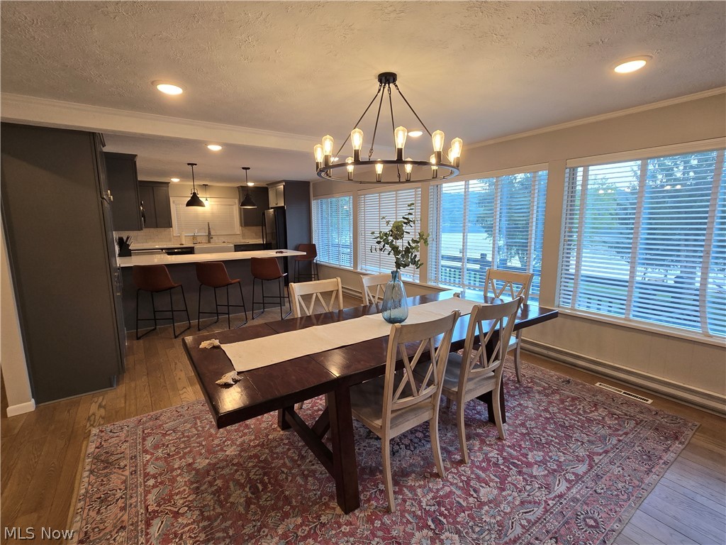 86450 Beaver Dam Road Scio, OH 43988 - Photo 16 of 28 Integrated dining area with wood-finish flooring, a contemporary chandelier, and a wall of windows