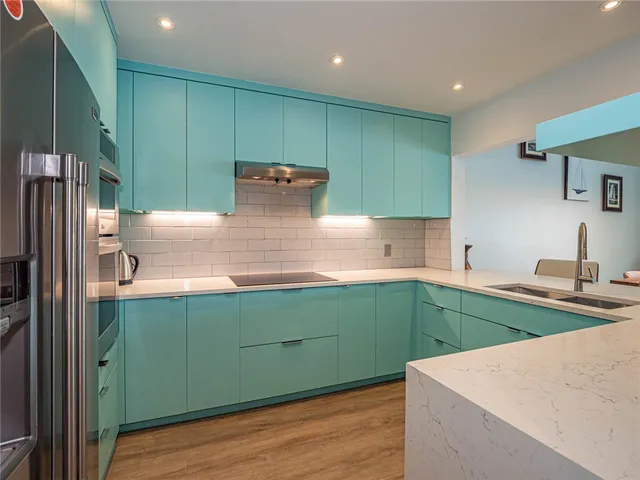 a kitchen with stainless steel appliances kitchen island a refrigerator sink and cabinets