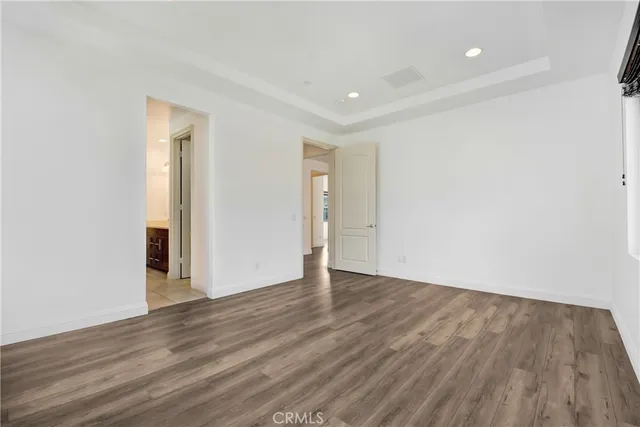 a view of an empty room with wooden floor and closet