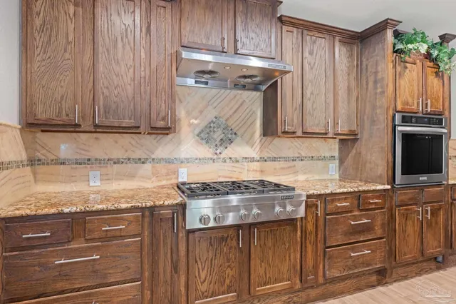a kitchen with granite countertop wooden cabinets and a stove top oven