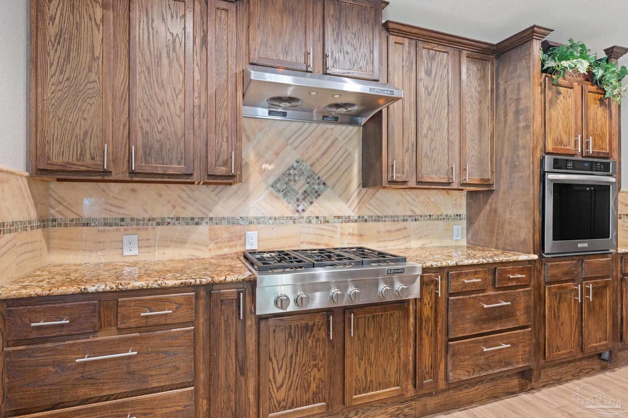 6781 Generals Lane Pace, FL 32571 - Photo 10 of 35 a kitchen with granite countertop wooden cabinets and a stove top oven