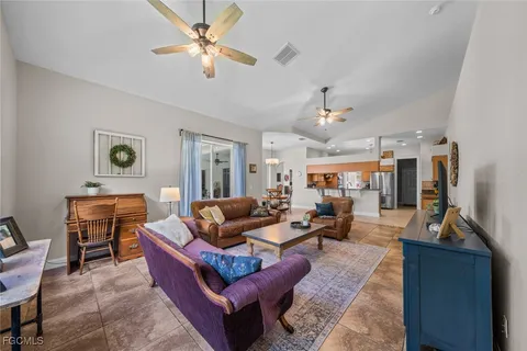 a living room with furniture kitchen view and a window