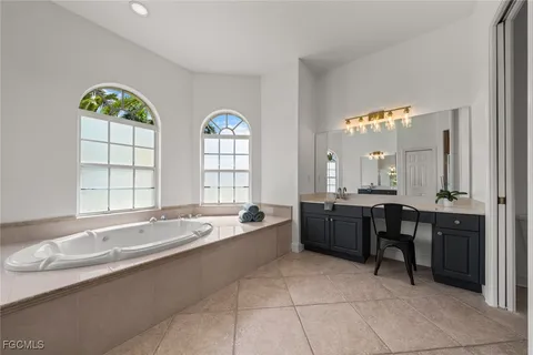 a large spacious bathroom with a granite countertop tub a double vanity sink a window and a shower